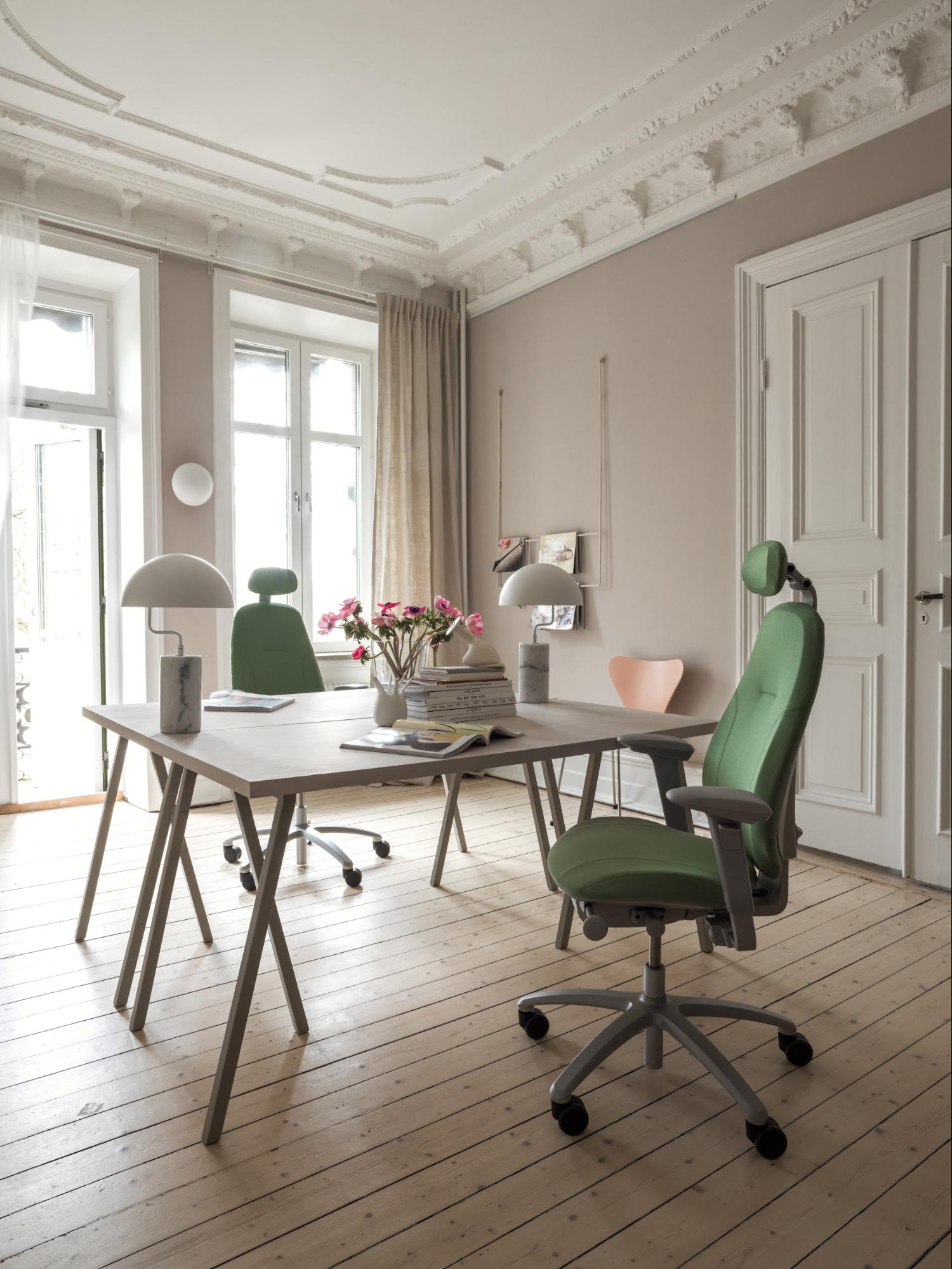 Image of a rose colored office with green office chairs.