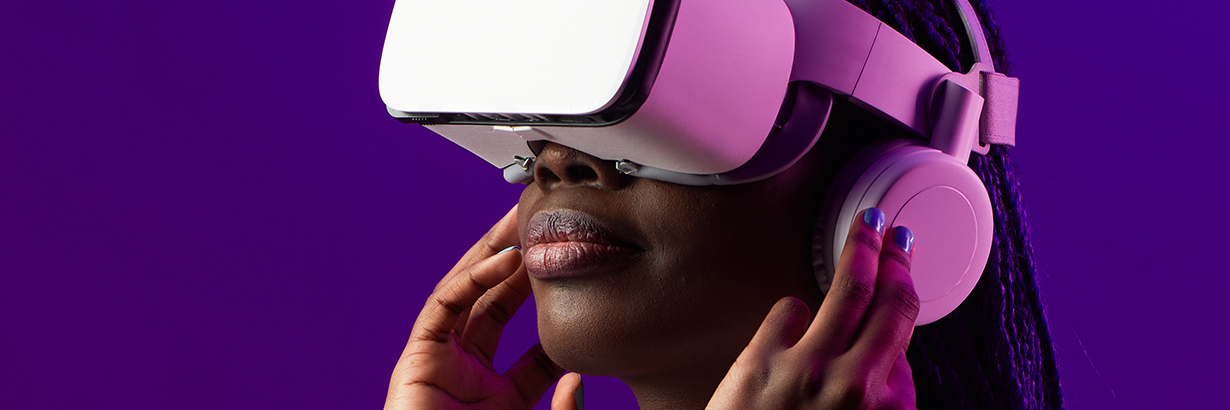 Girl wearing pink VR headset in front of a purple background.