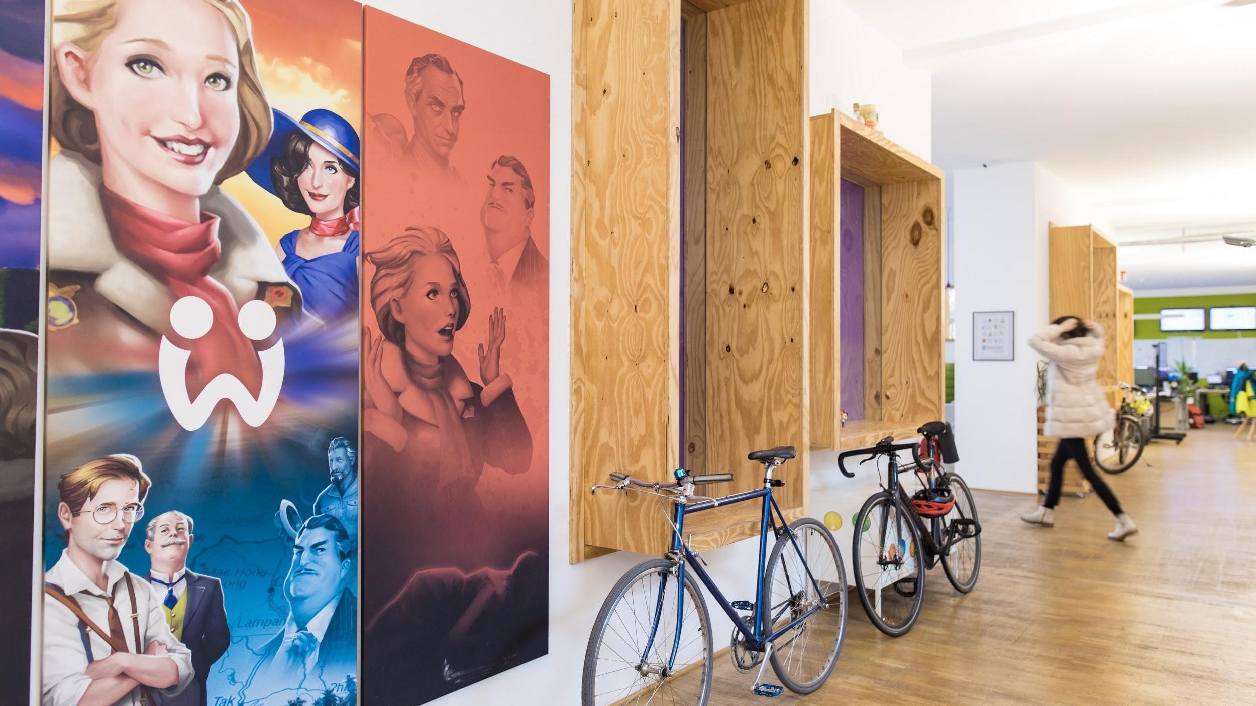 Hallway with large paintings of human faces and bicycles leaning against the wall