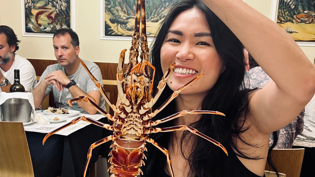 Tian Pei poses smiling at restaurant table with a crustacean