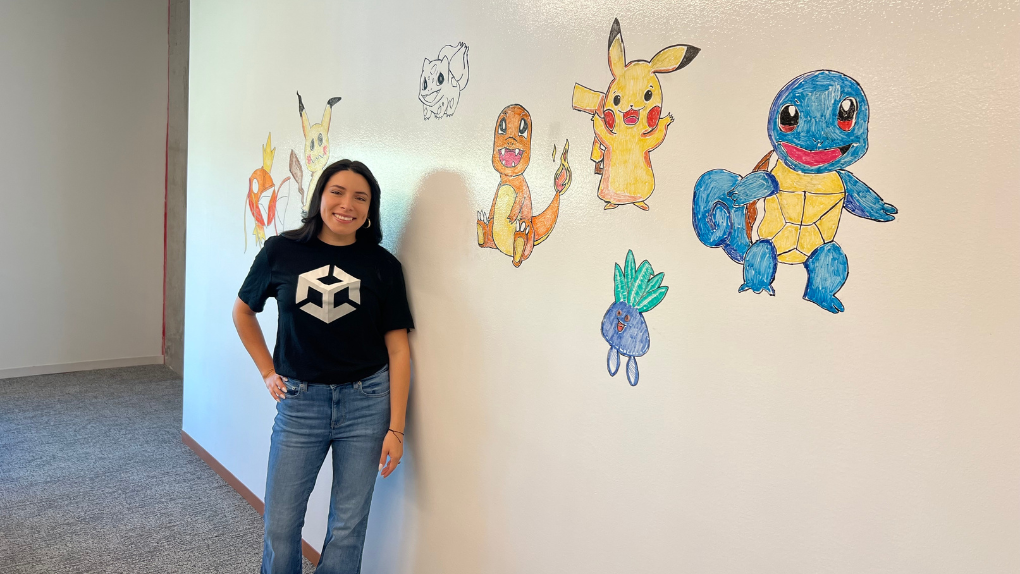 Esther standing in front of a whiteboard with staff-made drawings at the Unity Austin office