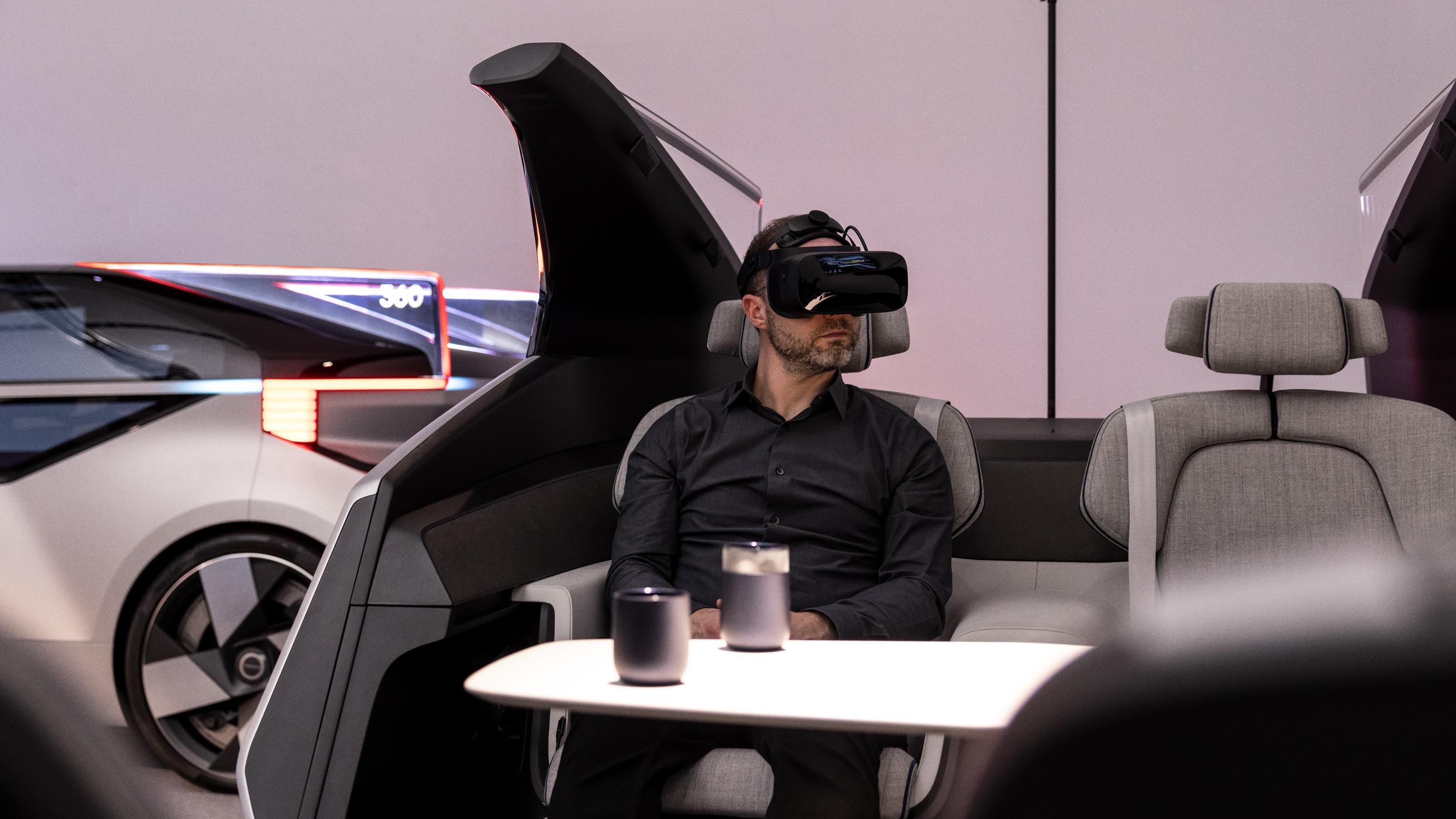 Person wears a mixed reality headset while seated inside a partial car cockpit.