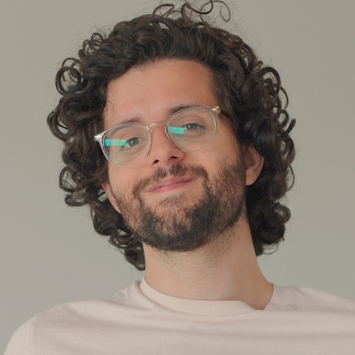 Smiling man with facial hair, curly hair, and glasses 