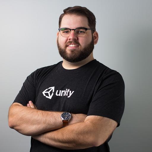 Bearded man with glasses smiling slightly wearing a Unity T-shirt