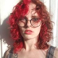 Woman with bright curly red hair and glasses