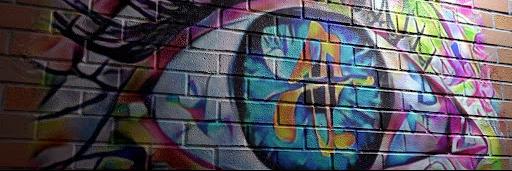 Street art depicting a large, multi-colored eye on a brick wall.