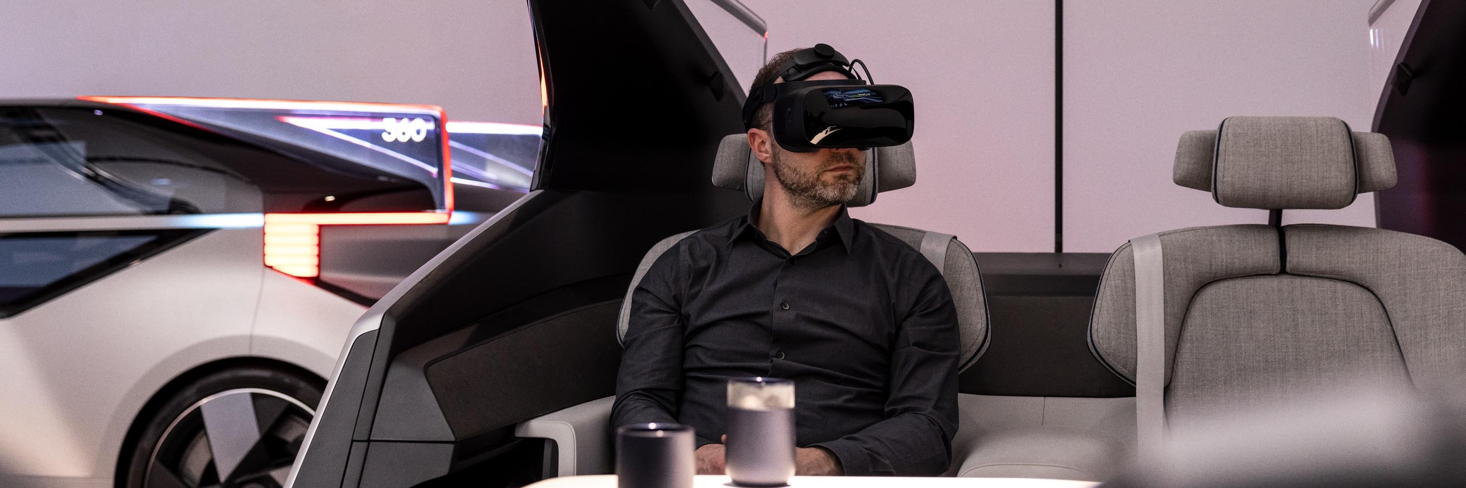 Person wears a mixed reality headset while seated inside a partial car cockpit.
